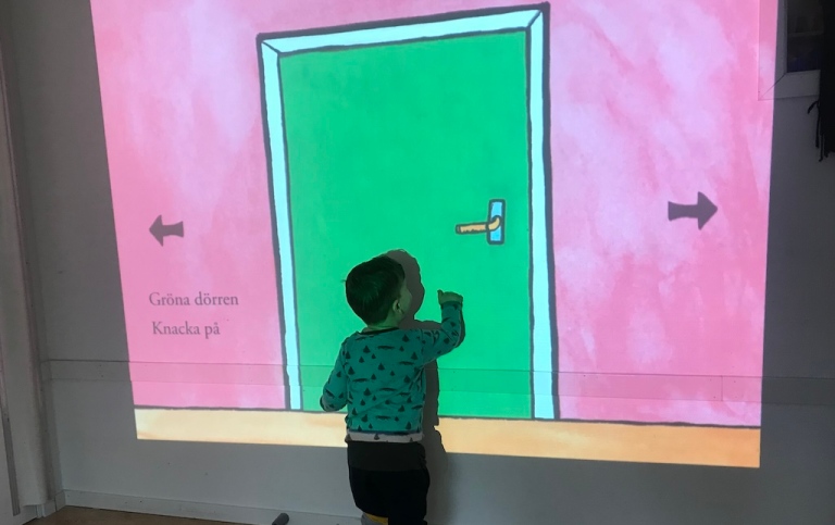 En dörr projiceras på väggen och ett barn knackar på den